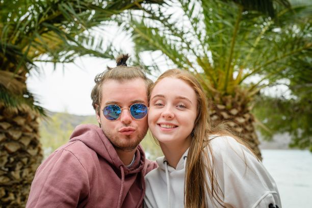 美丽的白人夫妇在棕榈树前摆姿势度假图片下载