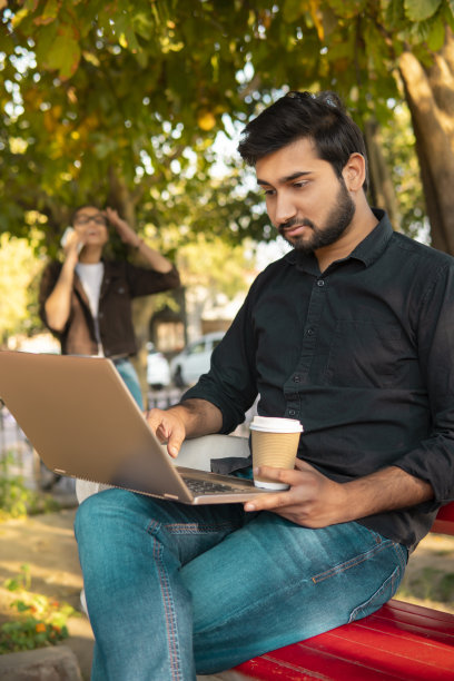 年轻的自由职业者，在新鲜的空气中喝着咖啡，用笔记本电脑工作。图片下载