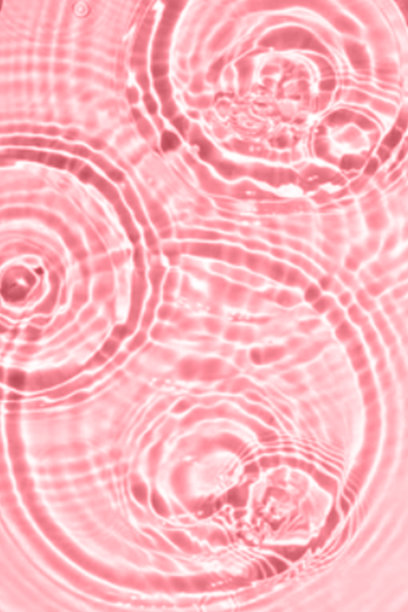 散焦模糊透明粉红色，清澈平静的水面纹理与飞溅和气泡。时髦的抽象自然背景。水波在阳光下复制空间。粉红色的水彩闪亮的图片下载