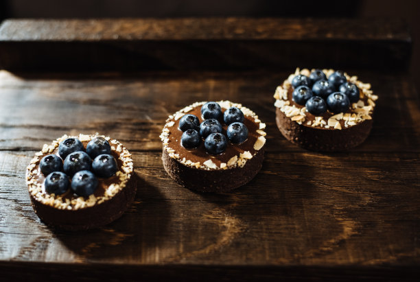 深色木质背景上点缀着蓝莓的巧克力馅饼。节日餐桌上的美味蛋糕。甜点配新鲜蓝莓。图片下载