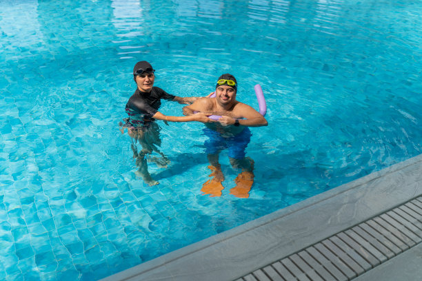 女教练在室内游泳池教唐氏综合征男孩游泳图片下载