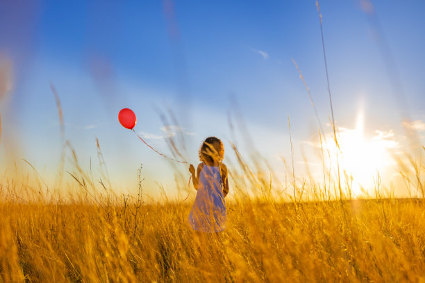 站在草地上的女孩抱着气球的背影图片下载