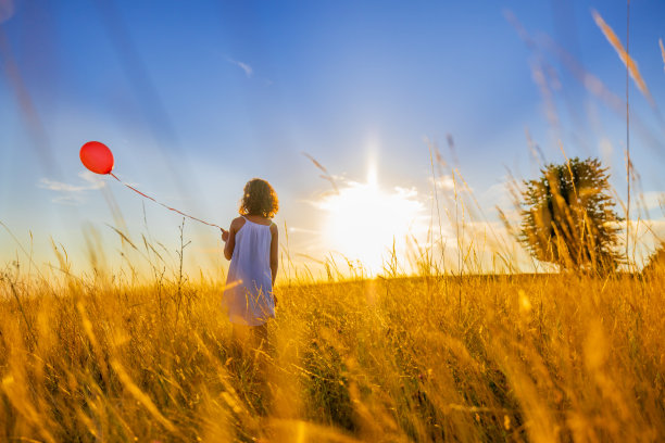 站在草地上玩气球的女孩的后视图图片下载