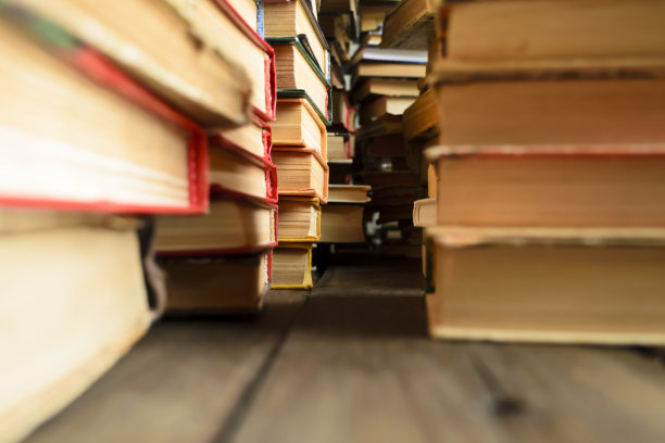 桌子上摆着一排排的书。书照片从下到上。桌上一堆书的微距摄影。木地板上有很多书。图片下载