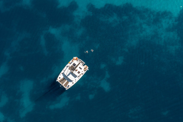 远处的人们乘着帆船在海上游泳的高角度视角图片下载