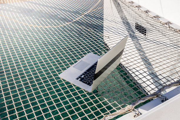 阳光明媚的日子里，船上甲板上的笔记本电脑在网上的高角度特写图片下载