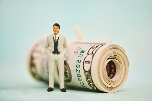 站在一卷美元旁边的商人。储蓄与金融主题图片下载