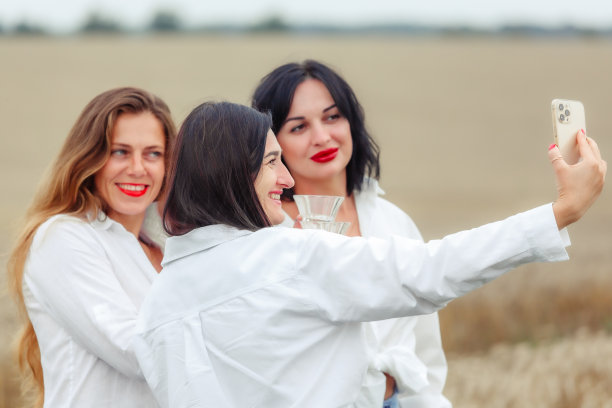 女朋友们喜欢喝白葡萄酒，微笑着自拍图片下载