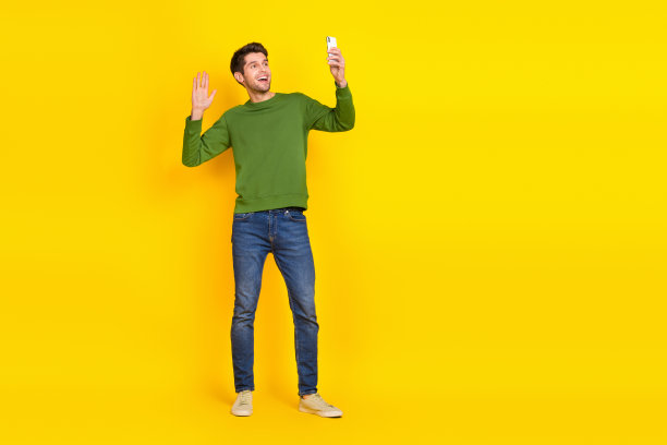 时髦兴奋的家伙穿绿色毛衣挥动手臂的照片照片现代小玩意空空间孤立的黄色背景图片下载