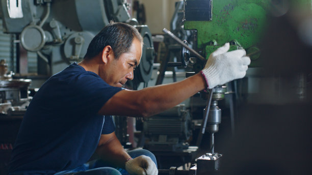 车间工人使用钻床进行金属加工图片下载