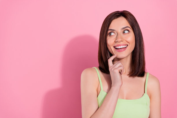 迷人梦幻的年轻女士的照片穿着绿色连衣裙微笑着看空的空间孤立的粉红色的颜色背景图片下载