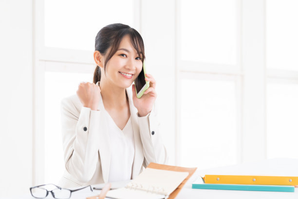 年轻的亚洲女人在电话上谈生意图片下载