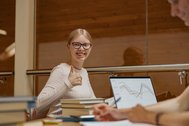 两个面带微笑的天才学生坐在图书馆里一起研究大学项目图片下载