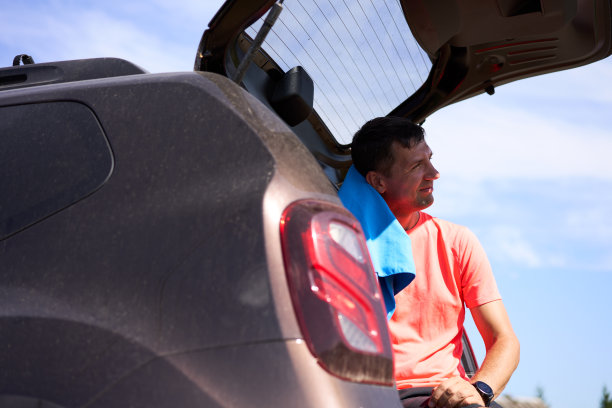 运动员坐在户外的行李箱里用毛巾擦汗。图片下载