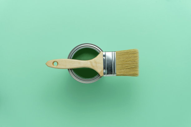 绿色油漆罐和木制画笔在海蓝色的背景。Diy、装修、家装理念。前视图。图片下载