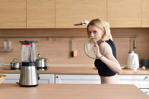 女人在厨房玩刀和锅盖，好像她是战士图片下载