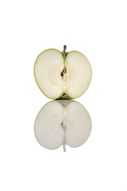 一个半青苹果在反射的白色表面上的垂直拍摄图片下载