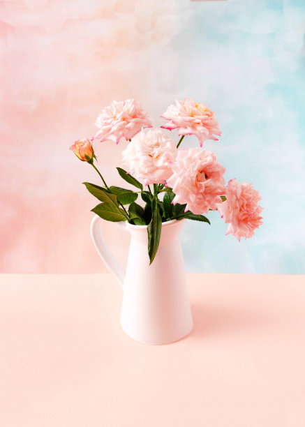 一束粉红色的玫瑰在一个白色的花瓶里，以淡粉色和蓝色为背景。浪漫的花卉概念，订婚或婚礼卡或邀请。创意理念为夏季花卉横幅图片下载