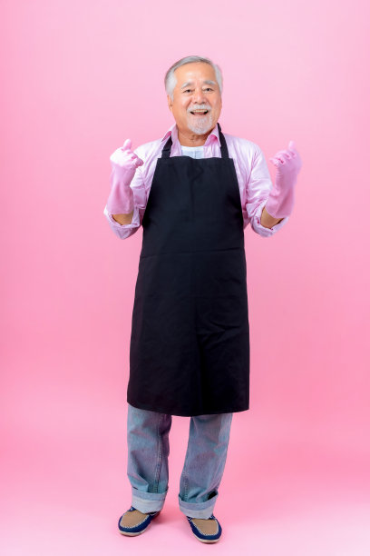 肖像迷人的亚洲退休老人有着白色的小胡子，戴着围裙的胡子尖手复制空间粉色的背景。图片下载