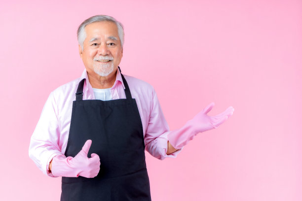 肖像迷人的亚洲退休老人有着白色的小胡子，戴着围裙的胡子尖手复制空间粉色的背景。图片下载
