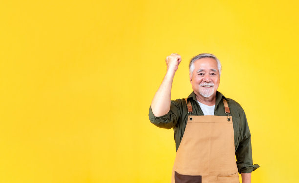 肖像迷人的亚洲退休老人留着白色的小胡子，戴着围裙指着胡子，双手临摹空间。图片下载