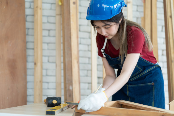 在木材车间，与机械师一起工作的女学徒木匠在丈量木材图片下载
