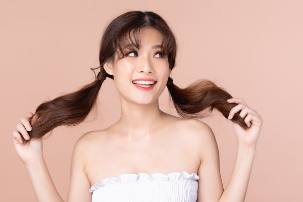 快乐开朗的年轻亚洲女性与两个辫子自然美容化妆，时尚模特，健康健康，美丽的女孩皮肤护理和面部治疗。孤立在米黄色粉红色的背景。图片下载