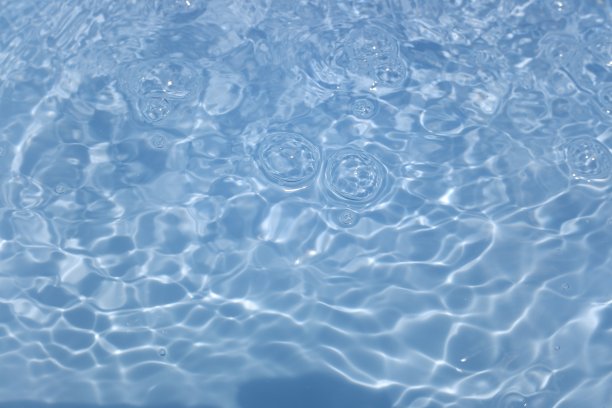 散焦模糊透明蓝色，清澈平静的水面纹理与飞溅和气泡。时髦的抽象自然背景。水波在阳光下复制空间。蓝色水彩闪亮的图片下载