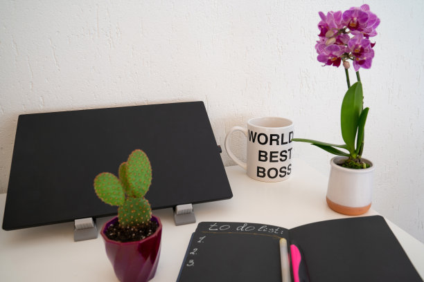 工作场所，舒适的工作区，办公桌上有笔记本电脑，笔记本做清单，笔和兰花花，工作氛围图片下载