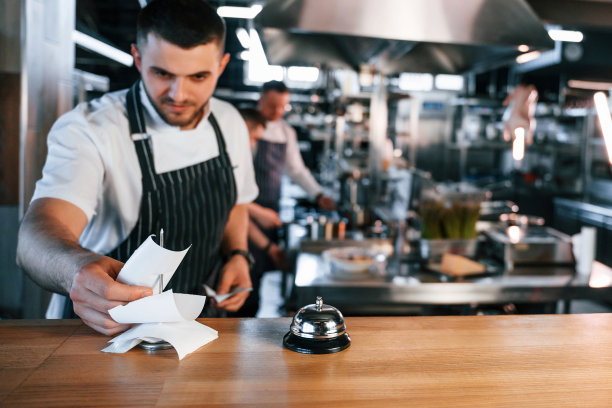 拿着铃铛站在桌边。厨房工作人员正在一起准备食物图片下载