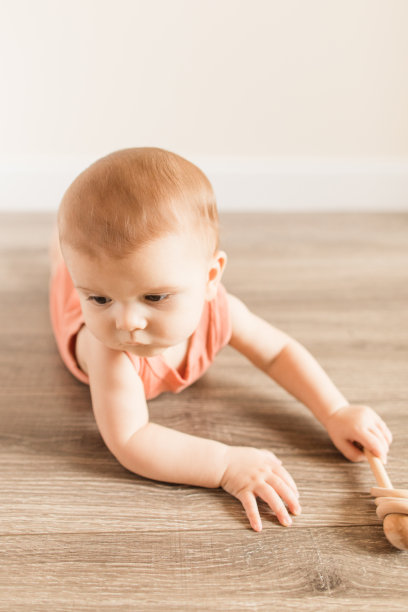 8个月大的大流行男婴，有12个脚趾，穿着写着“妈妈认为我是一个有趣的人”的鲑鱼色紧身泳衣，在木地板上玩的时候画上了蘑菇真菌图片下载