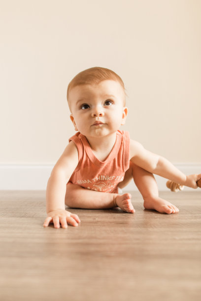 8个月大的大流行男婴，有12个脚趾，穿着写着“妈妈认为我是一个有趣的人”的鲑鱼色紧身泳衣，在木地板上玩的时候画上了蘑菇真菌图片下载
