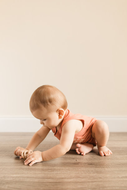 8个月大的大流行男婴，有12个脚趾，穿着写着“妈妈认为我是一个有趣的人”的鲑鱼色紧身泳衣，在木地板上玩的时候画上了蘑菇真菌图片下载
