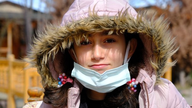 戴医用口罩的女孩很冷。图片下载