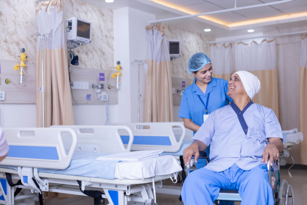 年轻护士在医院病房协助轮椅上的成年病人图片下载