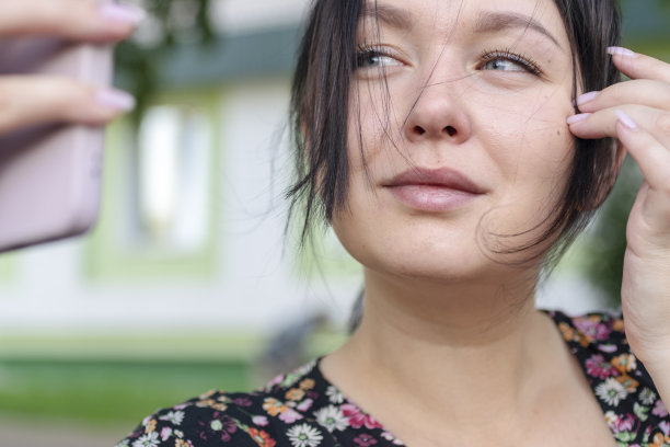 黑发女人看手机，就像看镜子。图片下载