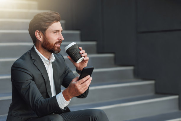 漂亮的上班族穿着西装，休息时坐在楼梯上喝咖啡，打电话图片下载