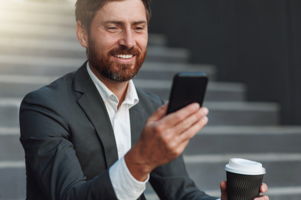 近距离微笑的上班族西装坐在楼梯上咖啡休息和使用电话图片下载