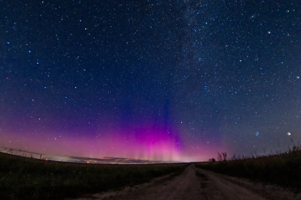 在星空和北极光下，一个孤独的人在田野里的夜间照片。天体摄影术图片下载