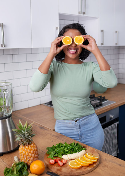 一位年轻的多民族妇女拿着橙子对着眼睛笑图片下载