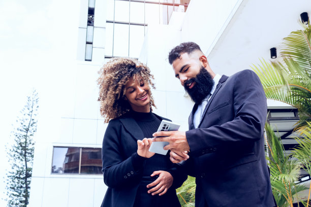 商务夫妇在公司大楼外。长胡子的白人男子向他的伴侣炫耀图片下载