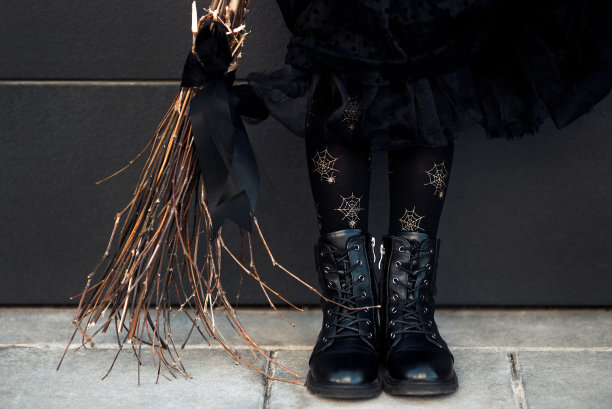 部分女性青少年服装万圣节派对黑色连衣裙，皮靴，紧身衣和手工扫帚图片下载