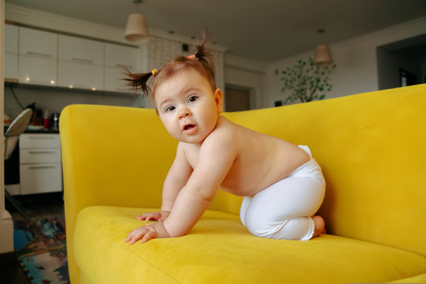 可爱的小女婴在黄色沙发上迈出了回家的第一步图片下载