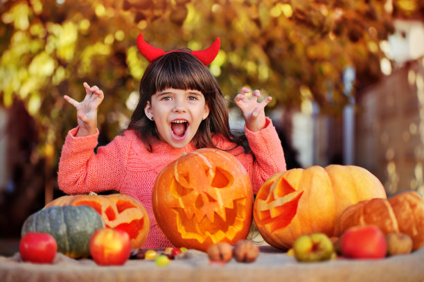 拿着万圣节装饰品的女孩做着可怕的手势，玩着不给糖就捣蛋的游戏图片下载