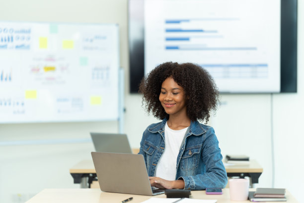 现代办公室:黑人女商人坐在办公桌前用笔记本电脑工作。成功的非洲裔美国女性与大数据电子商务合作。运动模糊的背景图片下载