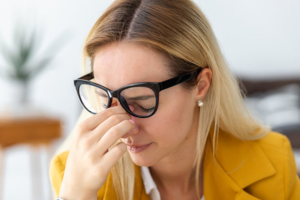 特写疲惫的压力妇女头痛感到恶心，疼痛，抑郁，过度工作的概念。一个戴眼镜的女人在他的鼻梁上蹭图片下载
