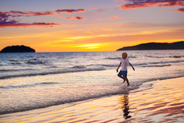 在海滩上玩耍的孩子。日落海的孩子。图片下载