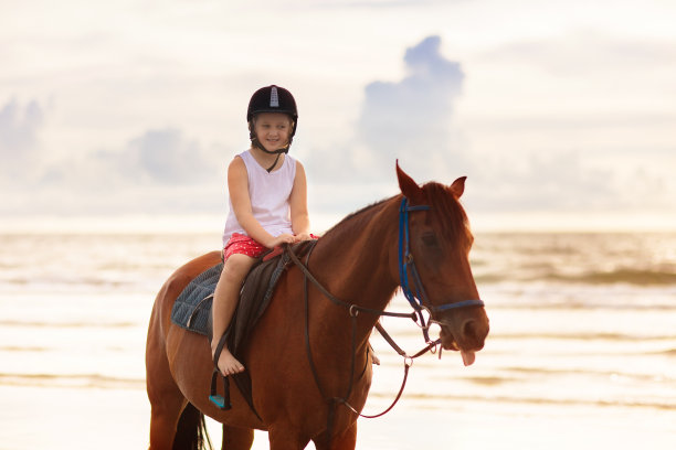 孩子们在海滩上骑马。孩子们骑马。图片下载