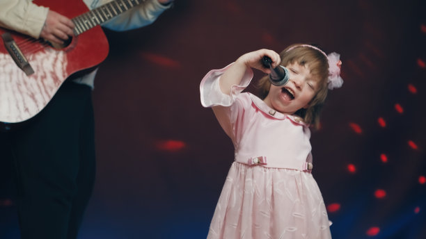 穿着复古礼服的小女孩在舞台上唱歌，她的父亲弹着原声吉他图片下载