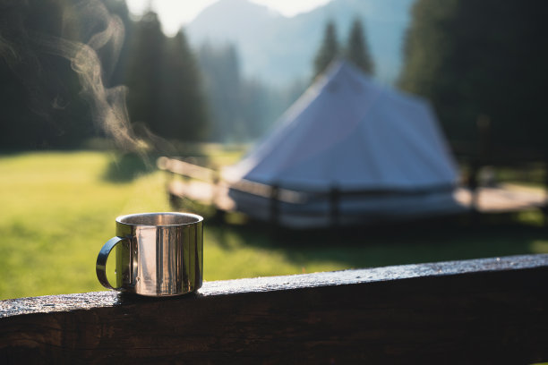特写的一个热气腾腾的金属杯与温暖的咖啡或茶在早晨与露营地的背景图片下载